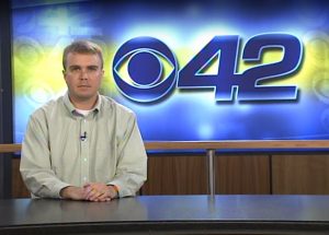 Michael at the anchor desk in front of the CBS 42 logo