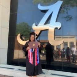 Crystal in front of a window with a Script A on it after Graduation