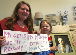 Kim and Autumn with a photo of Angel, holding up signs that say "My girls are my reason! My mommy did it! Master of Science"
